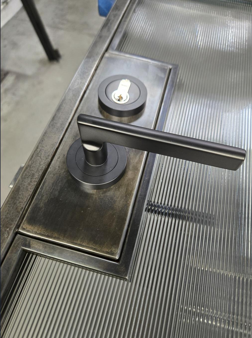 Black metal door handle and lock on a glass door.s