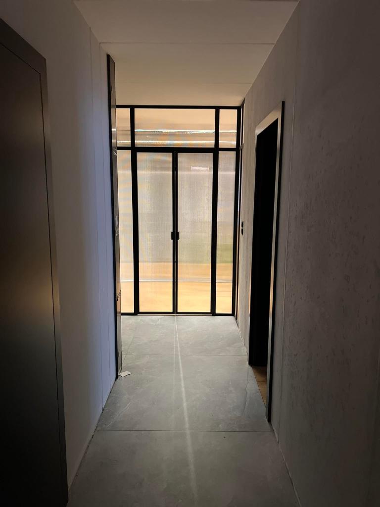 Hallway leading to a glass door with natural light beyond.